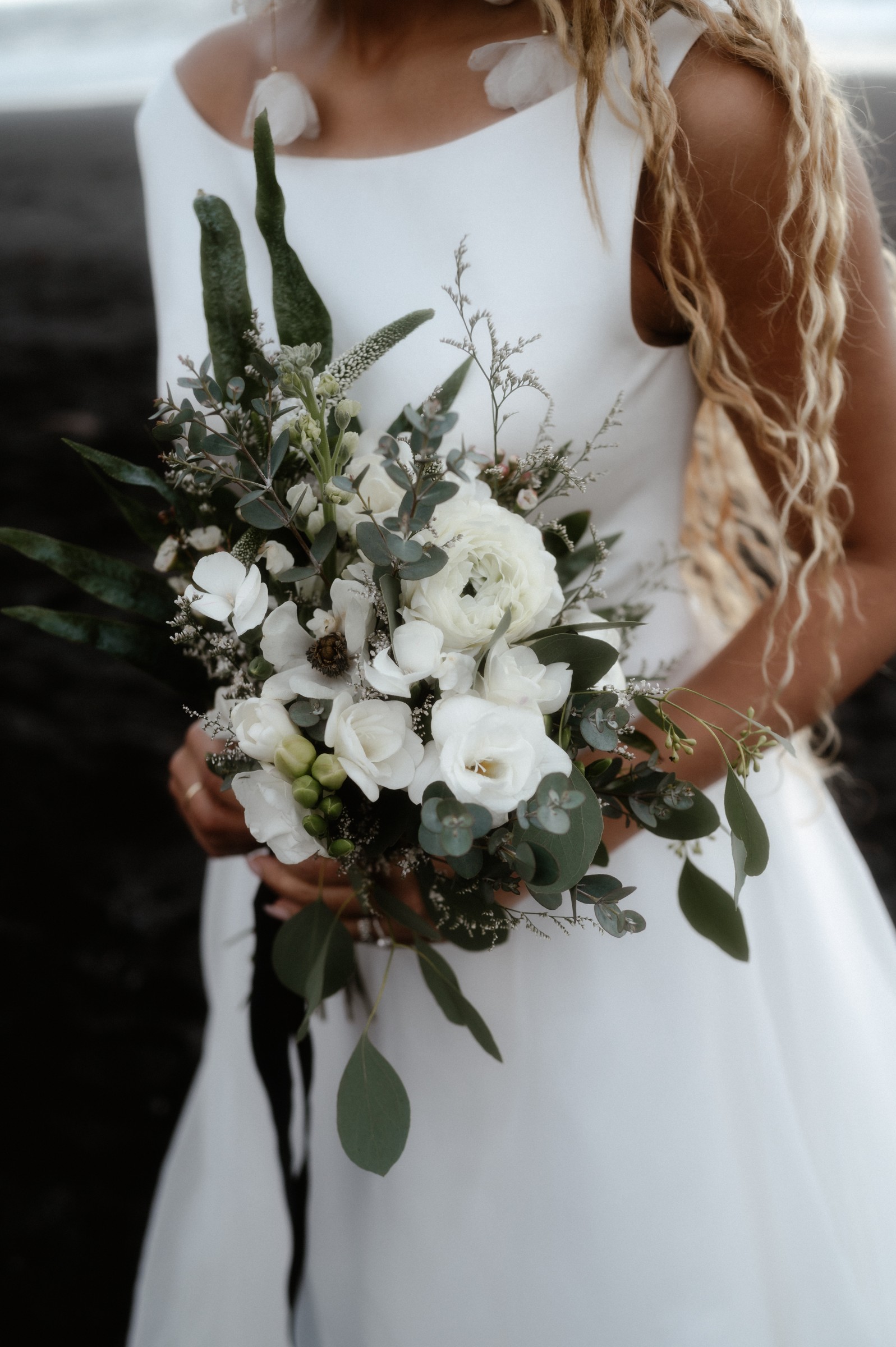 A bride holding a white flower and eucalyptus bouquet