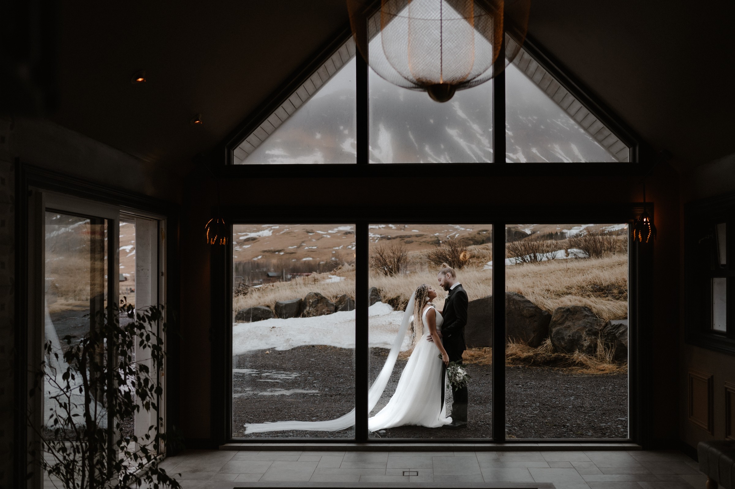 A wedding couple framed by the windows of an Icelandic venue