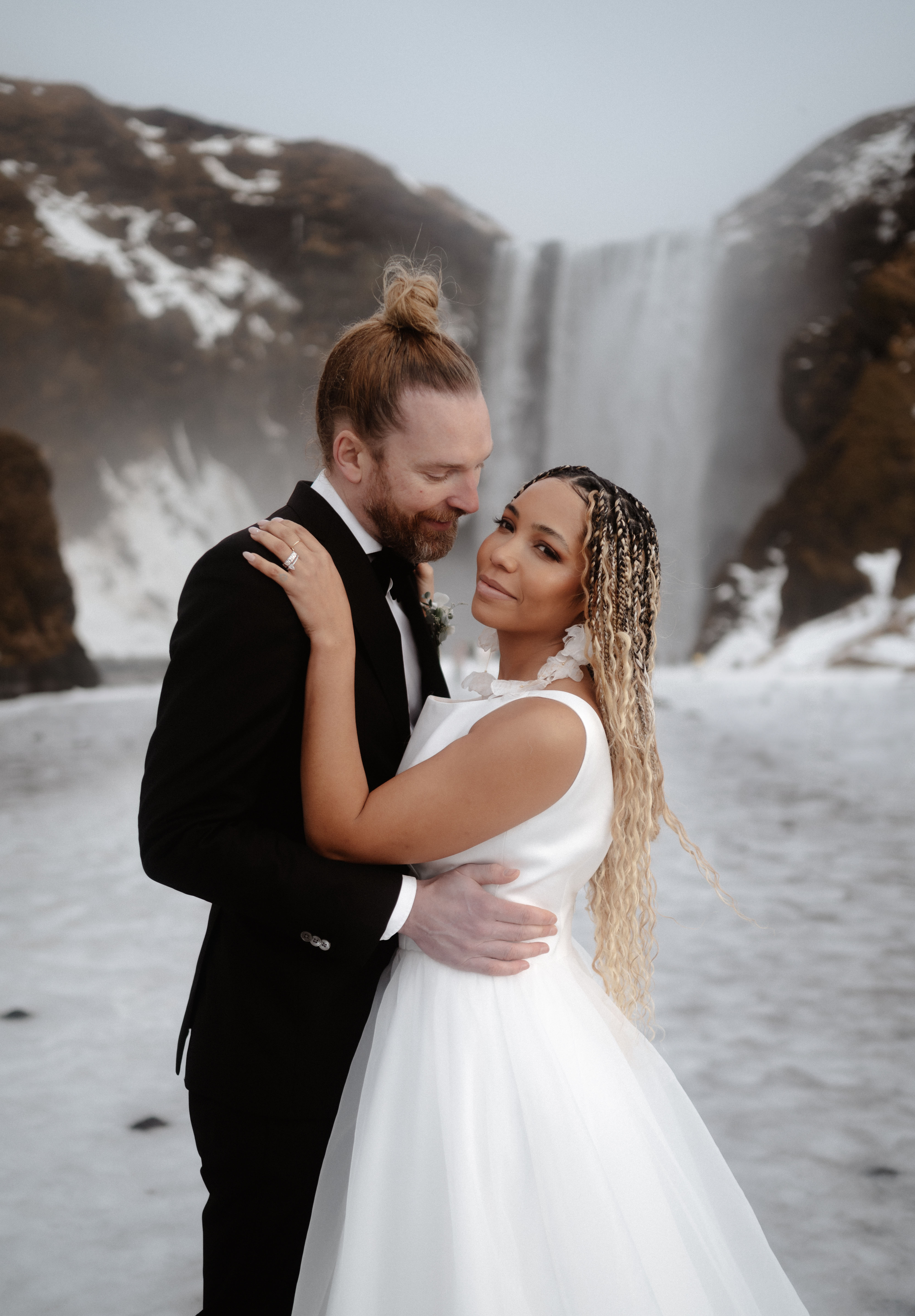 A couple embracing in front of an Icelandic waterfall