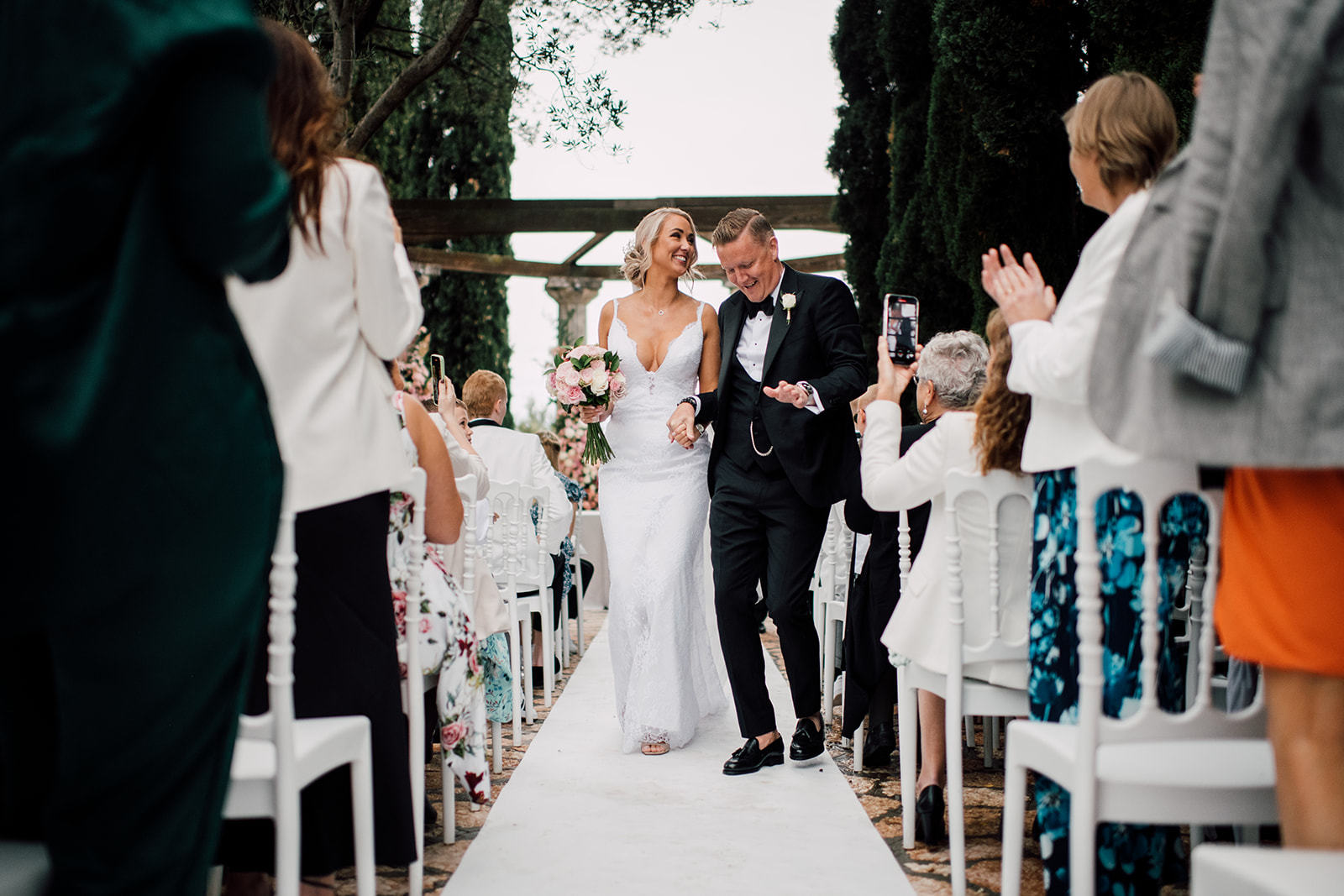 A newly married couple walking down the aisle surrounded by celebrating guests