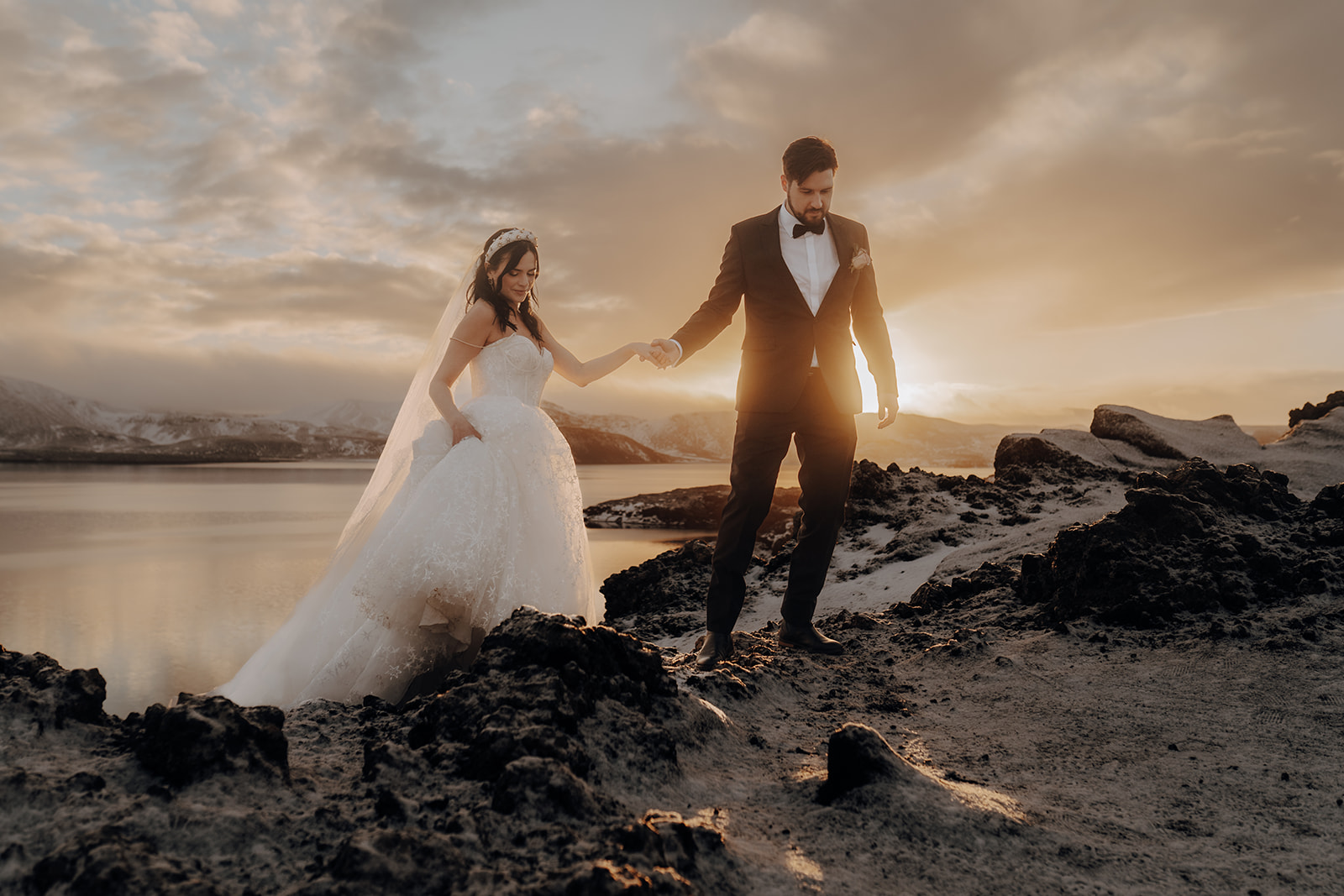 A couple holding hands by the water at sunset in Iceland