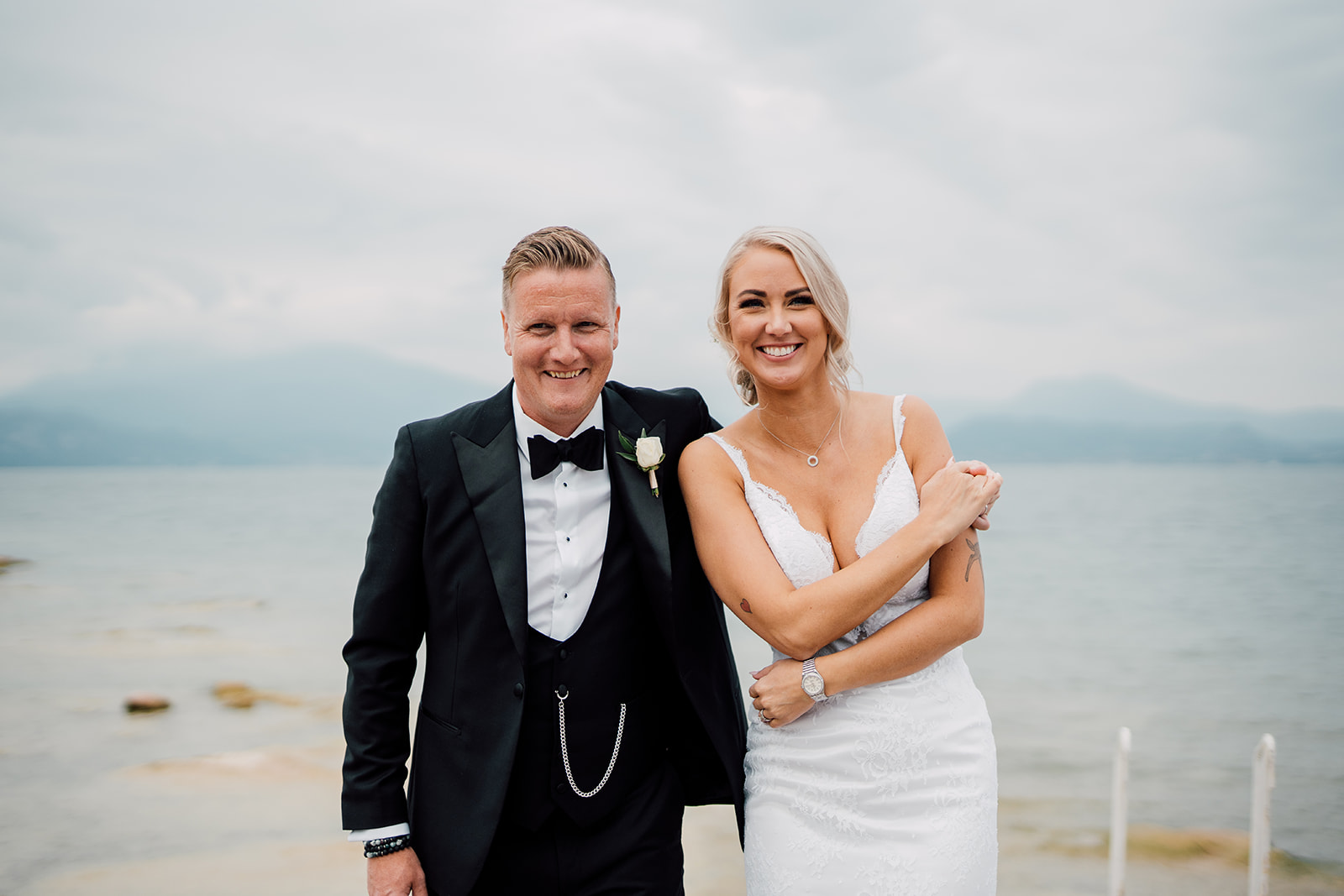 A smiling newly married couple beside a lake